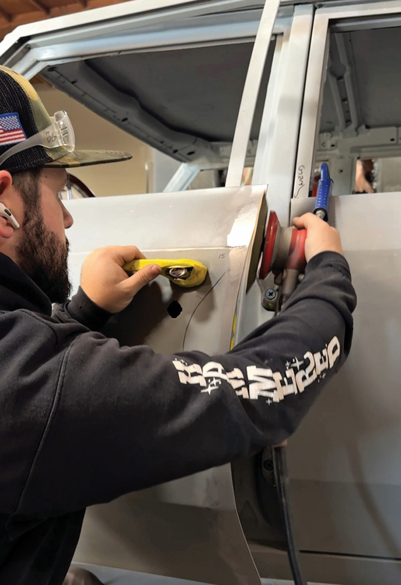 technician refining panel surface for smooth finish in the restoration shop
