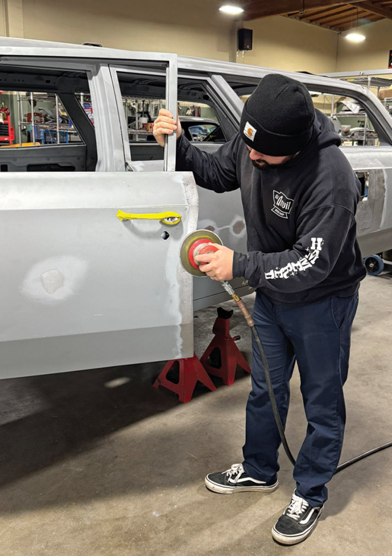 technician working with an orbital sander to refine the door panel surface