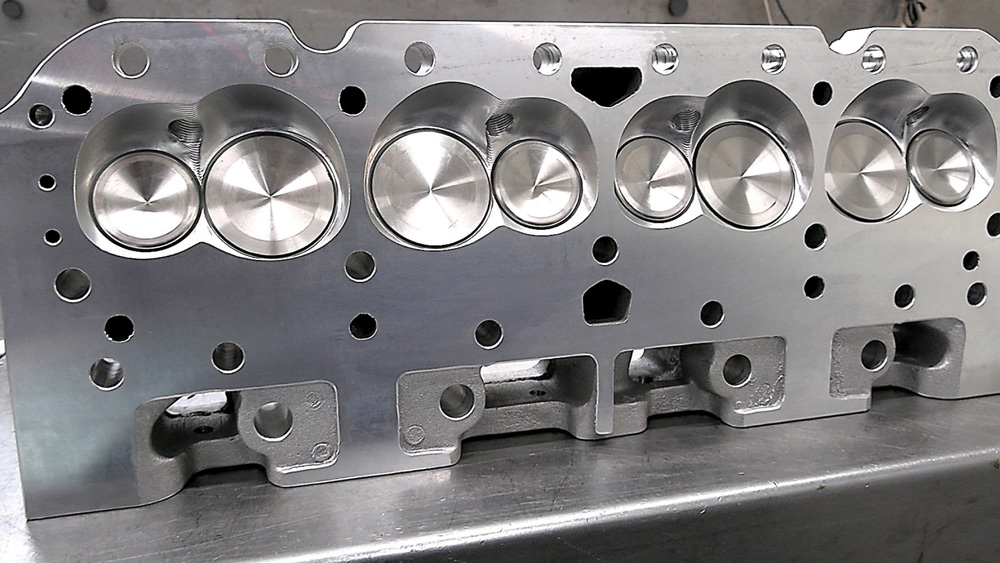 Machined aluminum cylinder head showing polished valve surfaces and port design