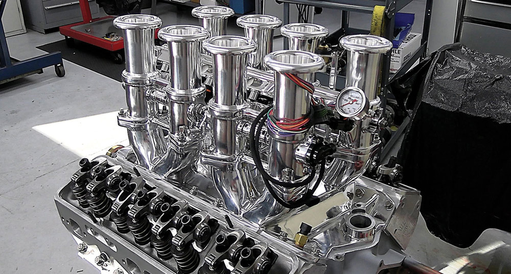 Polished individual throttle bodies on the Chevy 424 engine with visible fuel pressure gauge and wiring