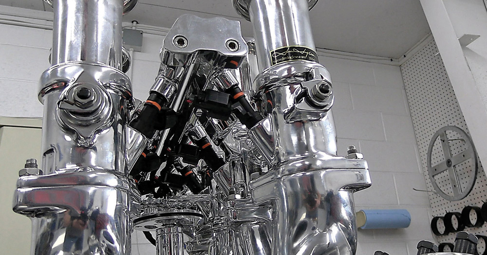 Close-up of polished throttle bodies with integrated fuel injectors and connectors