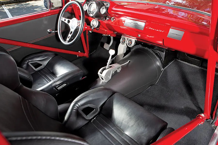 1957 Chevy Black leather interior with racing seats, a roll cage, and a B&M ratchet shifter