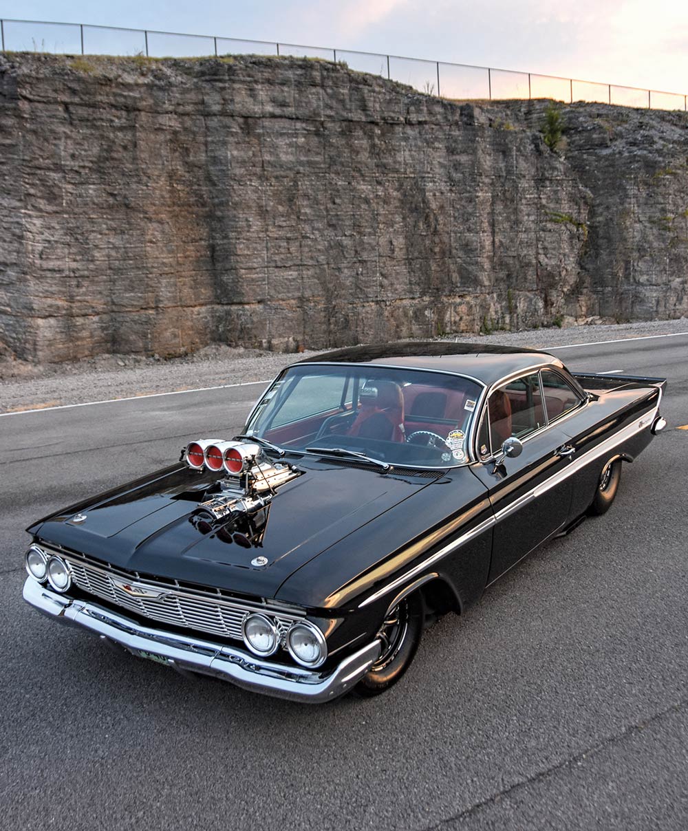 1961 Chevrolet Impala side profile showcasing a sleek hardtop design, polished trim, and aggressive stance on racing wheels