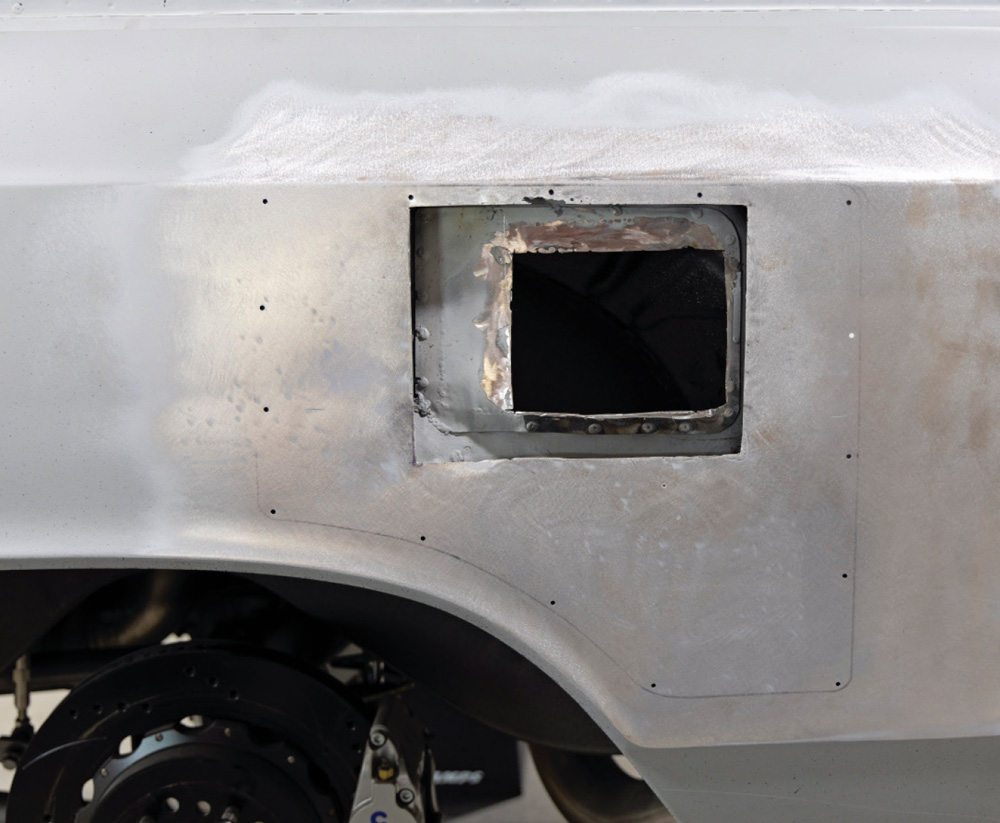 close-up of the cut-out fuel door area, revealing bare metal and precise weld marks for the modification