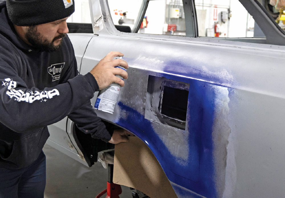 technician sprays layout fluid on the fuel door opening to mark precise cuts for a clean installation