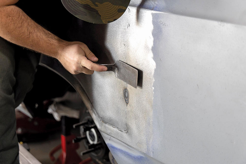 pneumatic sander smooths the surface, blending the repair seamlessly into the quarter panel