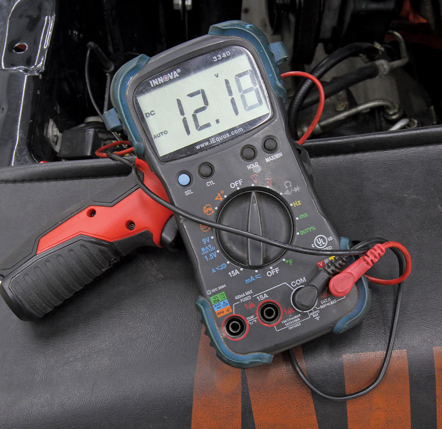 Innova digital multimeter displaying 12.18 volts during electrical diagnostics on a classic car