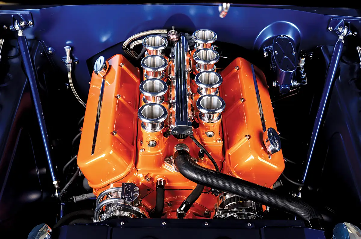 1966 Chevrolet Nova engine bay with a high-performance orange big-block V8 and velocity stacks