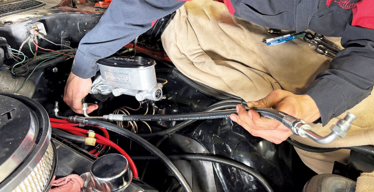 Mechanic routing new power steering hoses in the engine bay