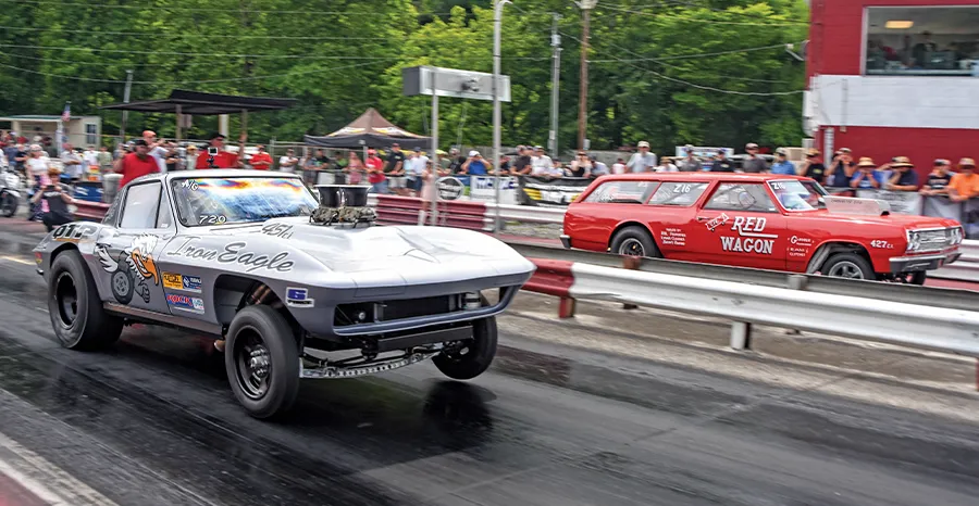 Two drag racing cars, a gray 'Iron Eagle' coupe and a red 'Red Wagon' station wagon, racing side-by-side on a track.