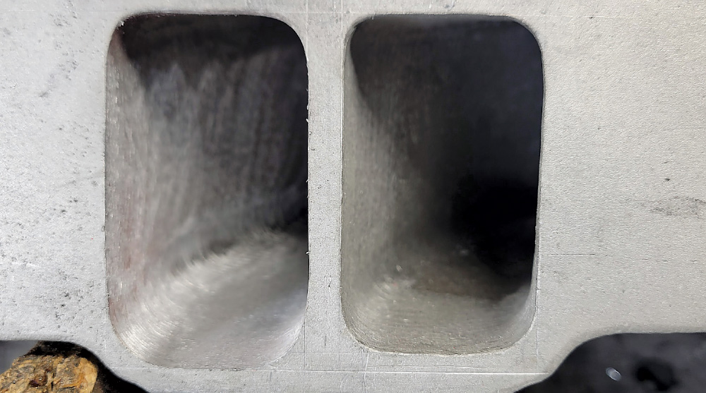 A close-up, top-down view of two rectangular, deeply recessed intake or exhaust ports within a metallic engine component, likely a cylinder head.