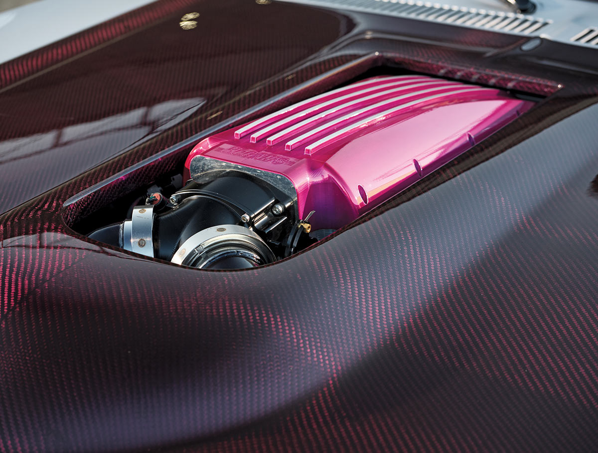 close-up of a limited-edition 1969 Nova's hood revealing a pink engine component within a carbon fiber setting