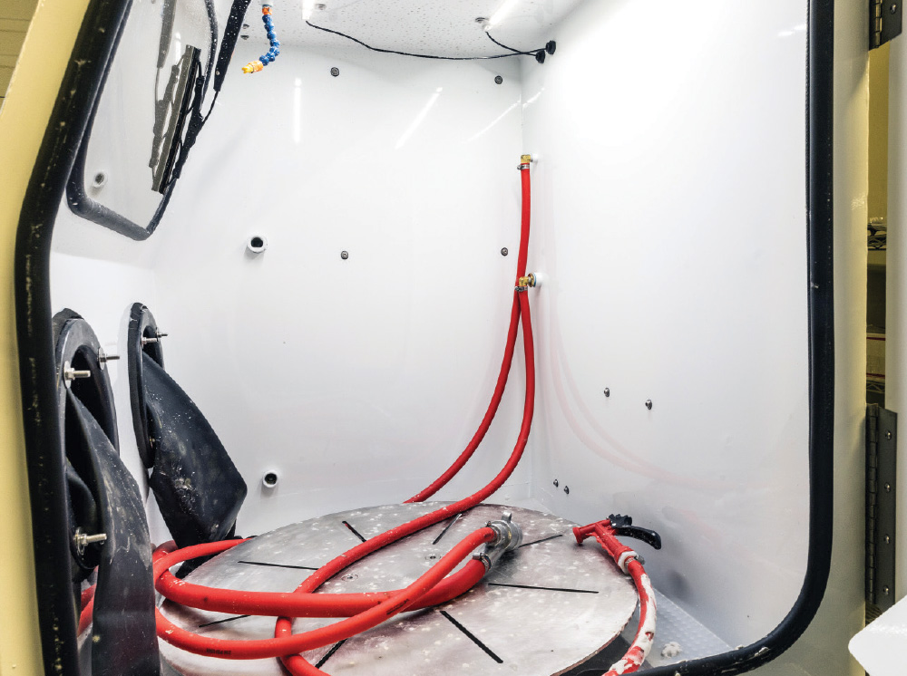 interior view of vapor honing cabinet with turntable and blast gun