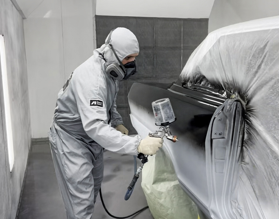 Painter spraying black base coat on 1963 Chevy Nova door