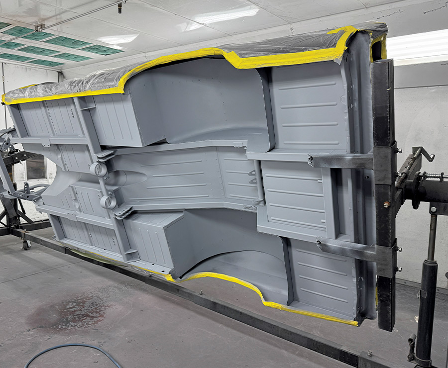 Undercarriage of 1963 Chevy Nova in gray primer rotisserie setup