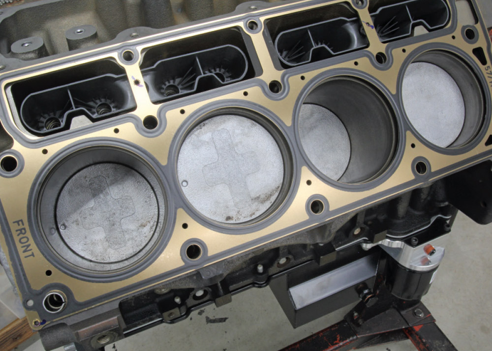 LS block with head gasket and pistons visible, lifter valley plugs in place