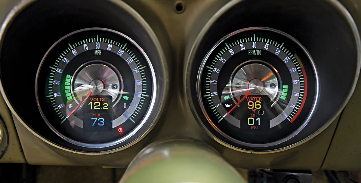 Close-up of a modern digital gauge cluster in a classic car, showing the speedometer, tachometer, temperature, oil pressure, fuel level, and volt readings.