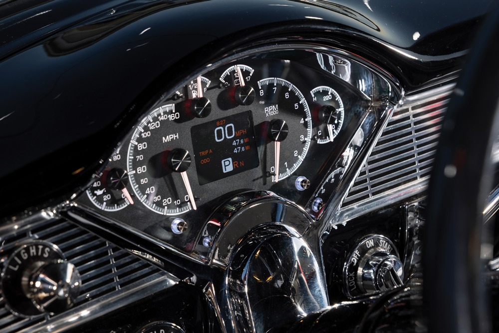 Detailed shot of the 1956 Chevrolet's custom gauge cluster, featuring a digital screen, large RPM and MPH dials, and a sleek, modern dashboard design.