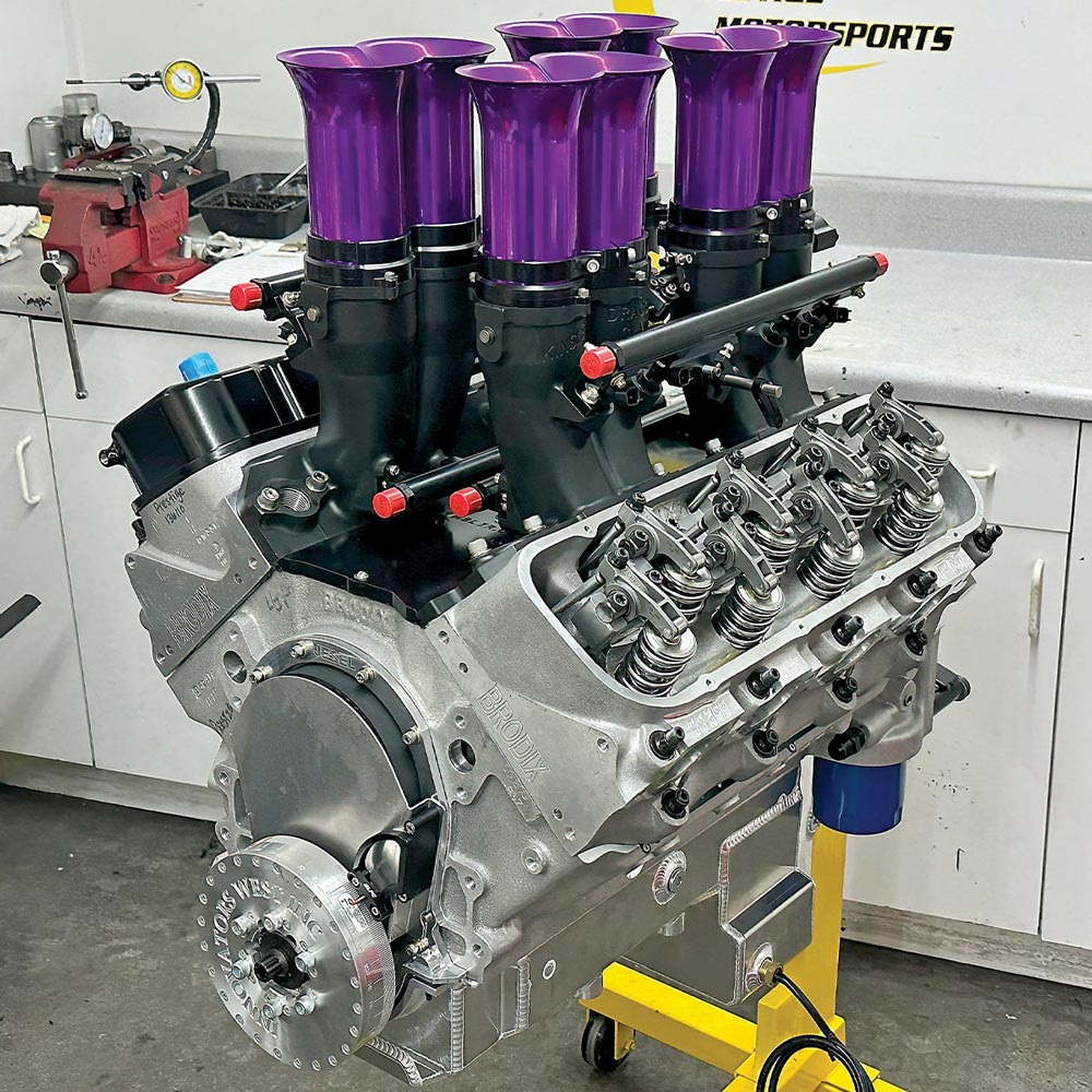 Prestige Motorsports' 582ci big-block Chevy engine on a stand. It features a gray block and a Kinsler Fuel Injection intake manifold with eight distinctive, vibrant purple velocity stacks.
