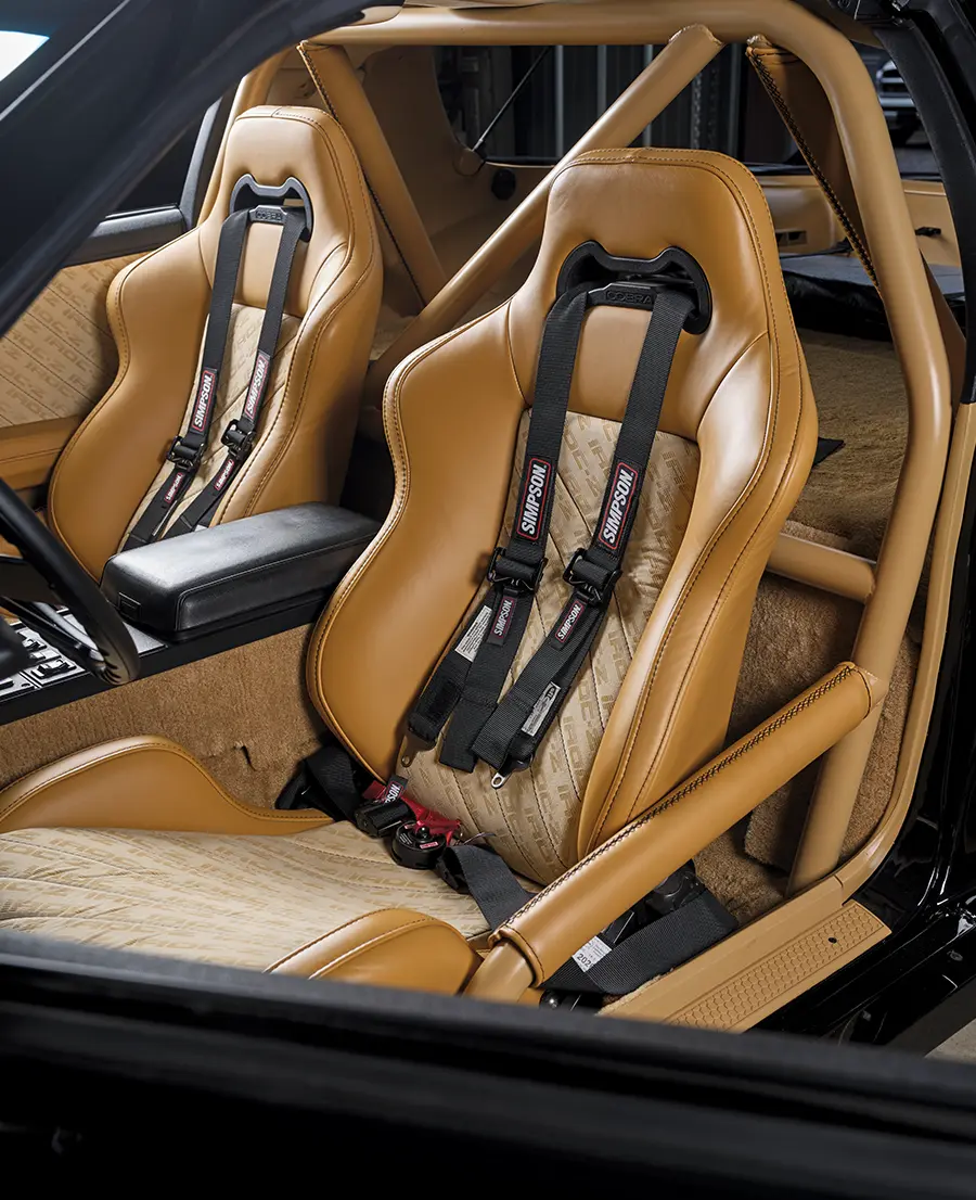 Custom tan leather Cobra racing seats with black Simpson five-point safety harnesses installed in a modified Chevrolet Camaro IROC-Z.