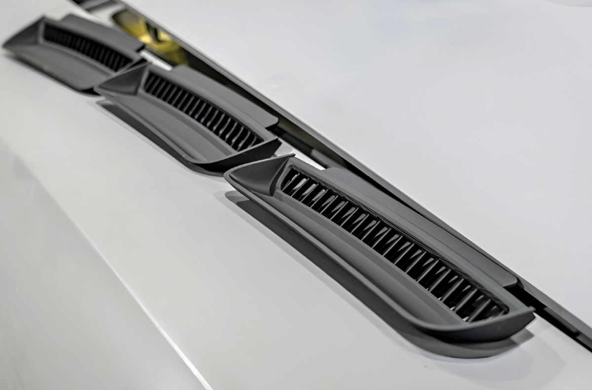Three black horizontal vents installed on the white surface of a car body.
