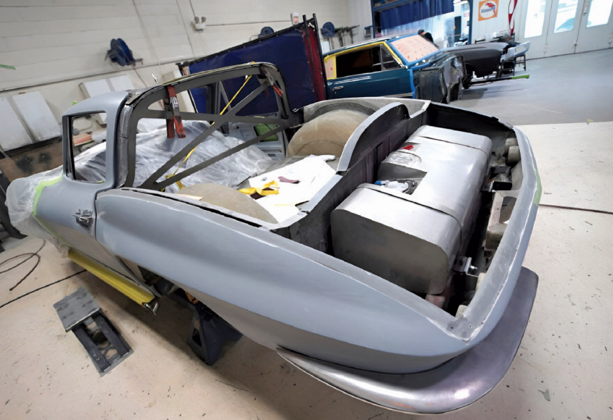 Classic car chassis in a garage with the body removed, showing the internal frame.