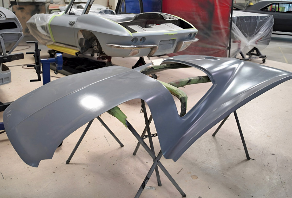 A grey car hood panel resting on a stand in a workshop.