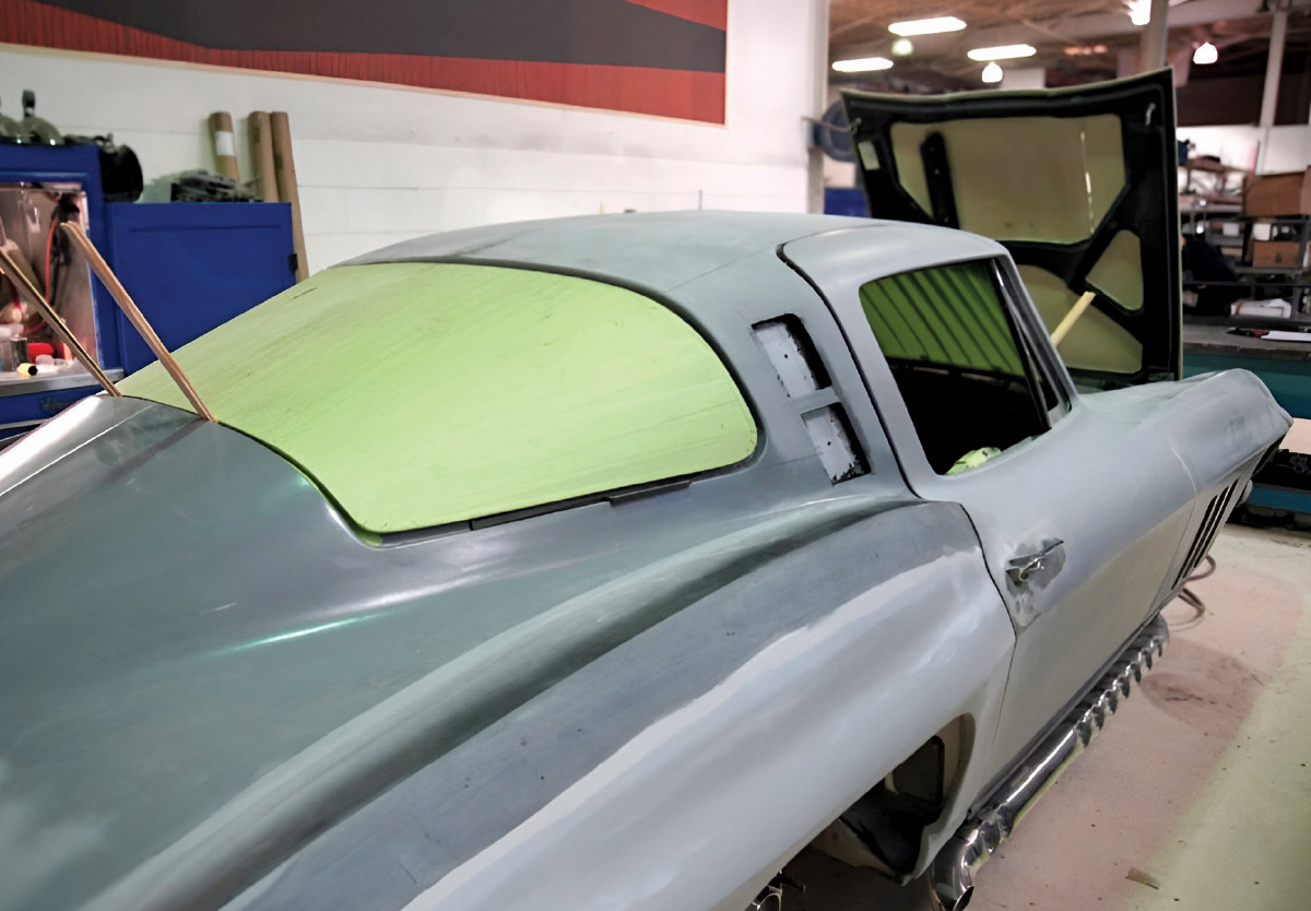 Rear view of a car body with the back window masked off with green paper.