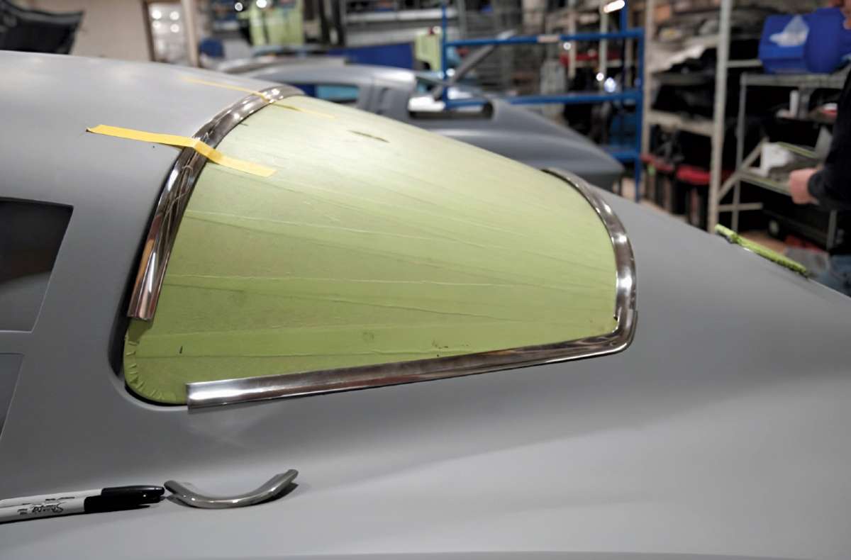 Rear window of a car featuring polished chrome trim being fitted.