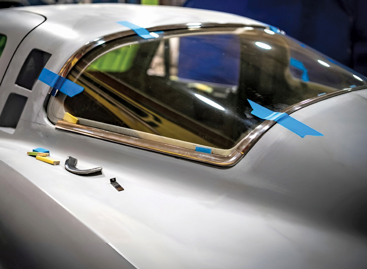 Detail of rear window glass and chrome trim secured with blue painters tape.
