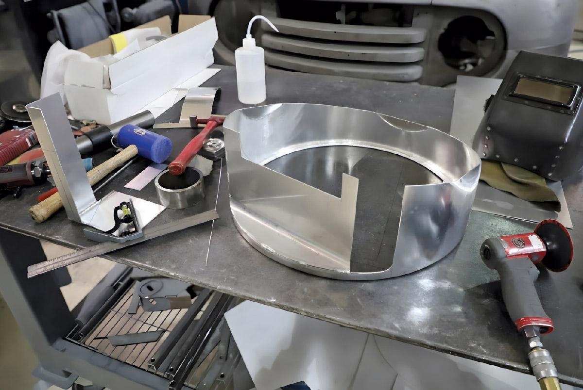 Various custom-fabricated aluminum shroud pieces and tools on a metal workbench.