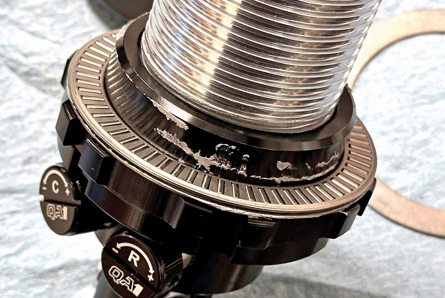 Close-up of a QA1 adjustable coilover shock absorber featuring dual adjustment knobs for compression and rebound tuning on a performance suspension system