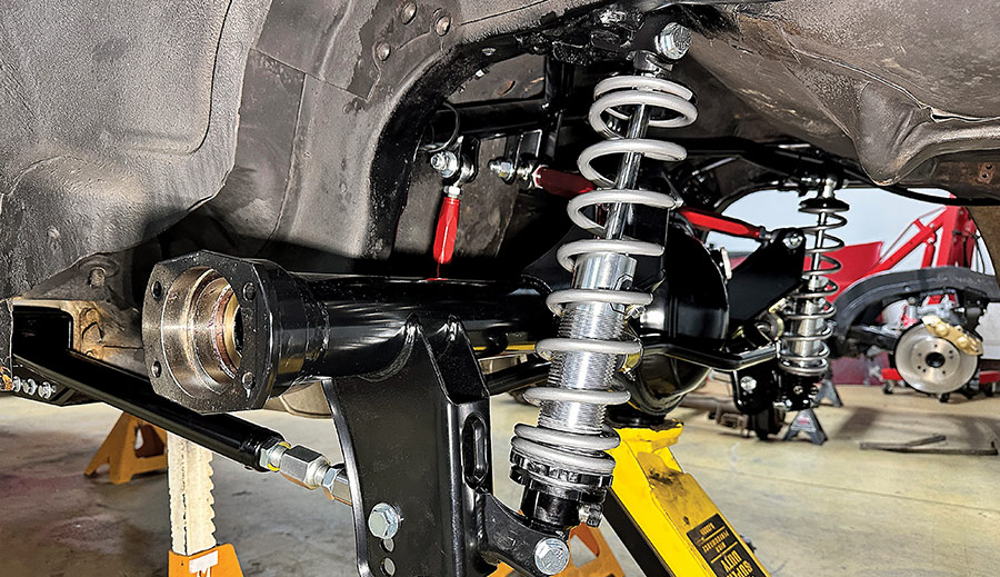 A detailed view of a newly installed QA1 rear coilover suspension on a classic Chevrolet Camaro, featuring silver coil springs, adjustable shock absorbers, and a black Ford 9-inch rear axle housing