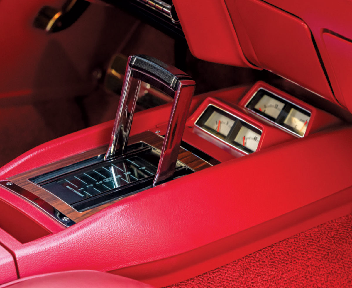 Close-up of the center console featuring a chrome automatic shifter and auxiliary gauges set in a woodgrain trim.