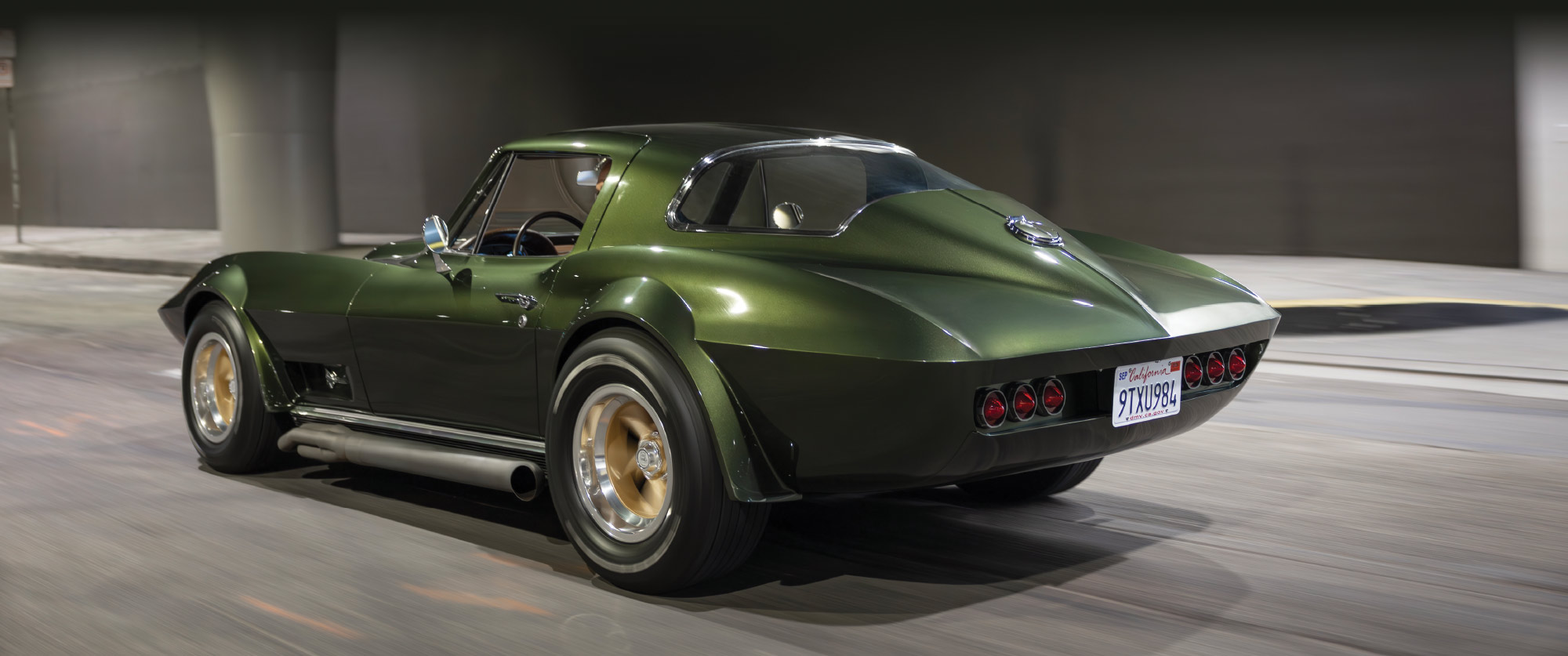 Rear three-quarter view of the green Corvette showing its rounded rear window and classic taillights.