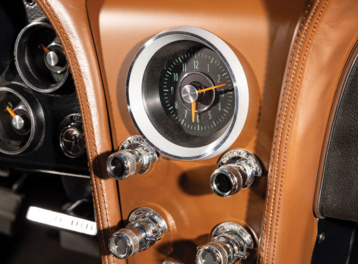 Close-up of the center dash clock and chrome pull-knobs set in tan leather.