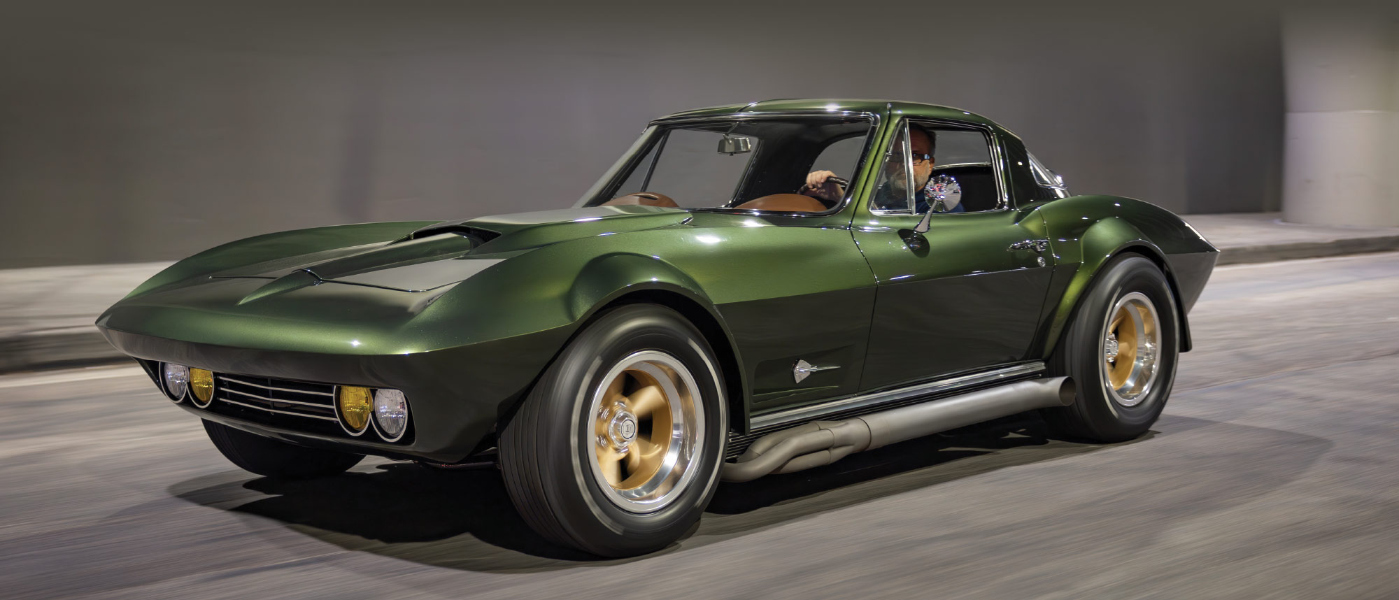 Side action shot of the green Corvette driving through an urban setting.