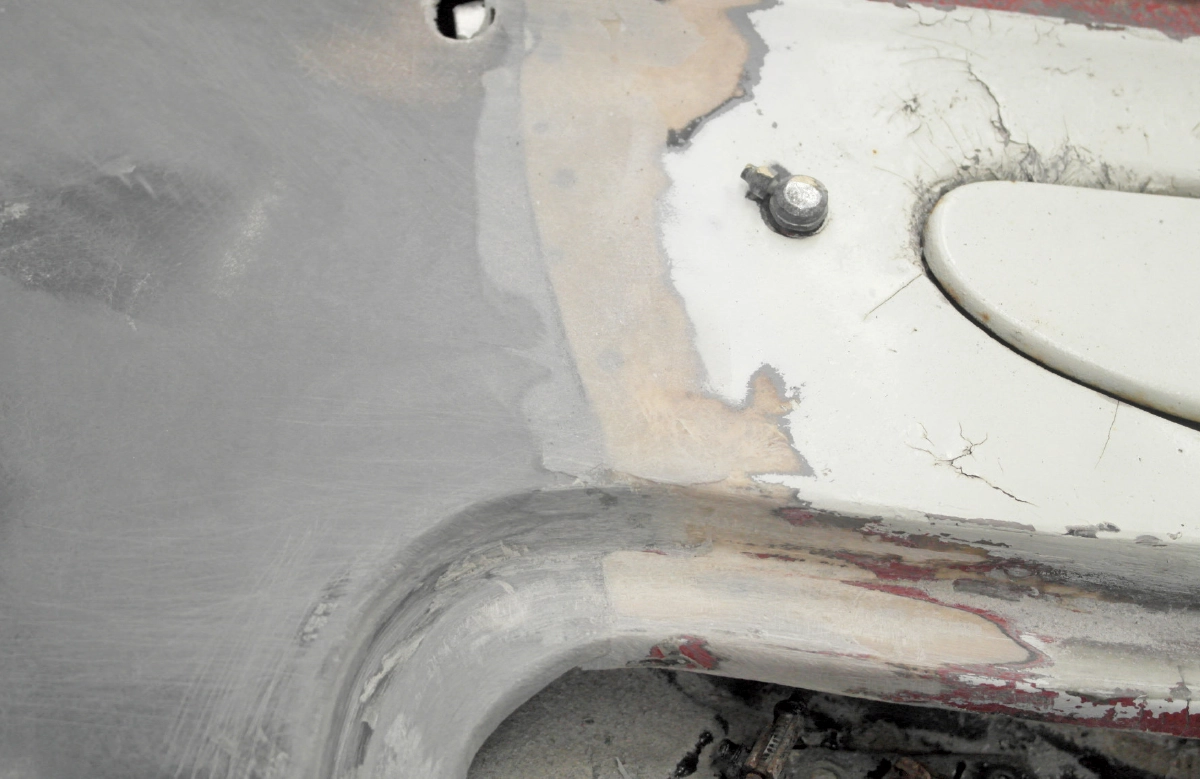 A close-up view showing the finished, smoothed edge of the grey fiberglass panel where it meets the original bodywork, with a transition between the old and new materials
