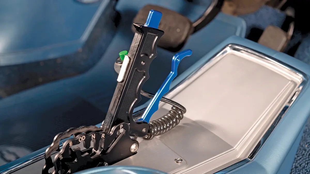 Detailed close-up of a custom performance automatic pistol-grip shifter with blue and green controls and a 1-P shift gate, mounted in a car's console