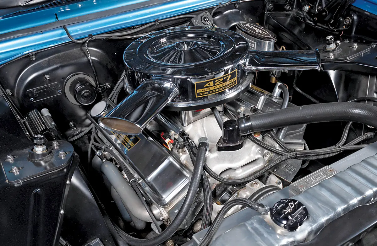 Close-up of a high-performance 427 fuel-injected V8 engine with a chrome dual-snorkel air cleaner and polished valve covers in a clean black engine bay