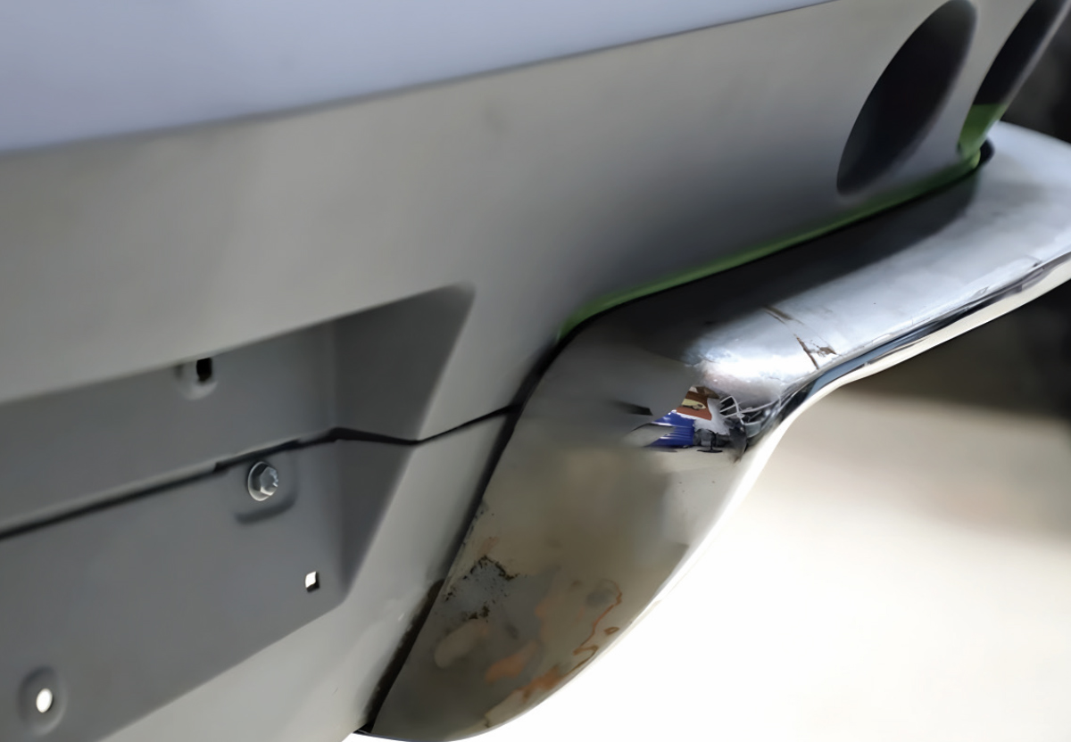 Close-up view of a metal bumper corner fitted against a grey primed body panel. The image demonstrates a tight, uniform gap between the bumper edge and the car's body line.