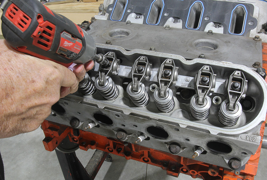 Mechanic removing rocker arms using a power tool.