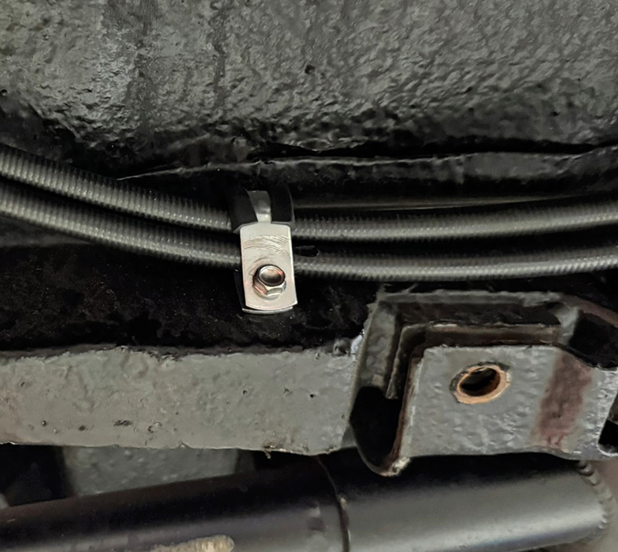 Rubber-coated clamp securing brake cable housings.