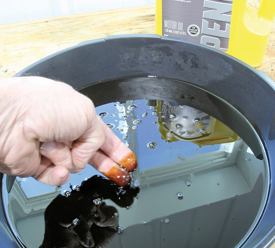 Technician inspecting used motor oil for the scent of raw gasoline.