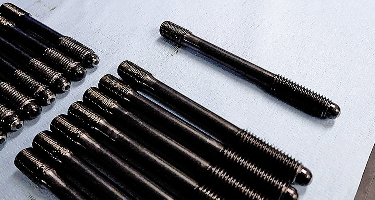 Set of black undercut main studs on a blue surface.
