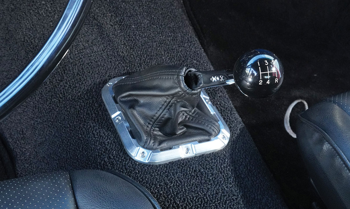 Five-speed manual gear shifter detail in black leather boot.