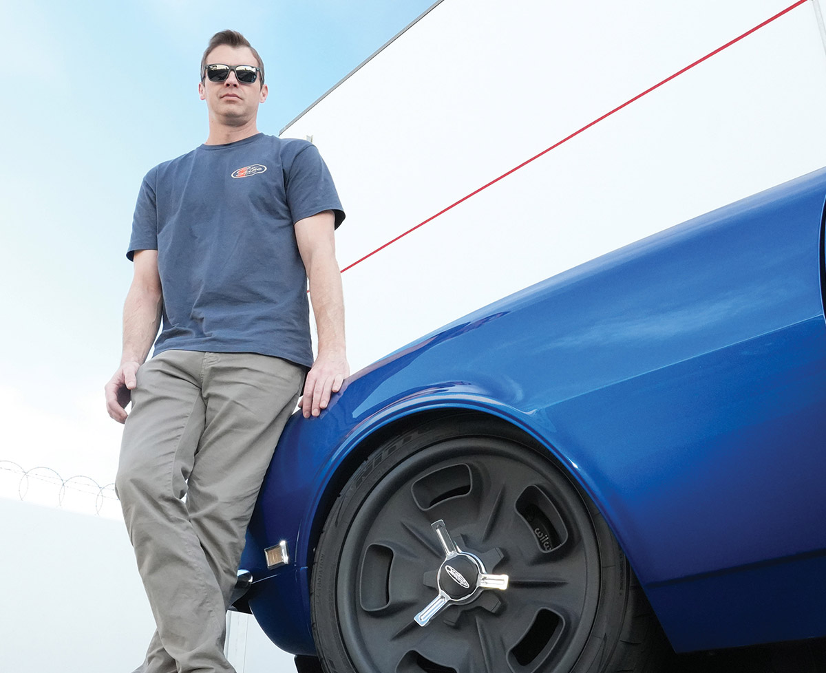 Owner Andrew Topolski leaning on his blue Camaro.