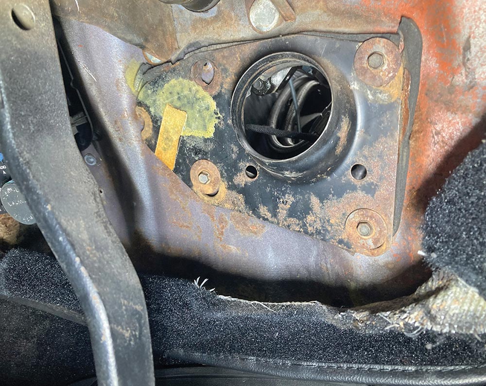 Rusted firewall opening lacking proper steering column support.