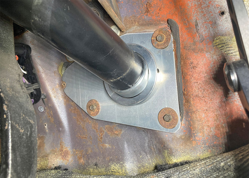Swivel floor mount bolted to the steering column at firewall.
