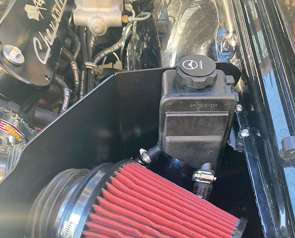 Black plastic reservoir mounted next to a red air filter.